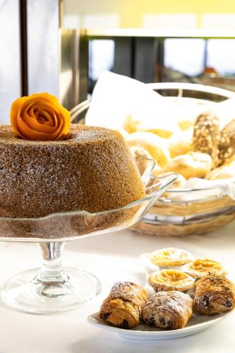 a cake on a plate on a table with pastries at Hotel Black Tulip - Porto Gaia in Vila Nova de Gaia