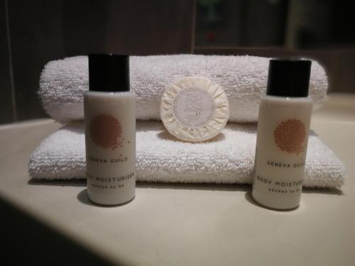 three bottles of moisturizers sitting on top of towels at Hotel Brise de Mer - Piscine intérieure & extérieure in Saint-Raphaël