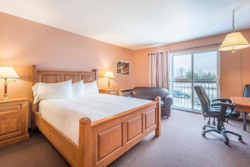 a bedroom with a bed and a desk and a window at Hotel Baie Saint Paul in Baie-Saint-Paul