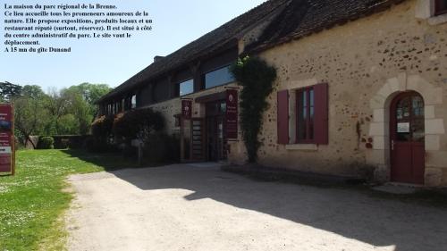 an old building with red doors and a dirt road at Gite rural DUNAND in Tournon-Saint-Martin