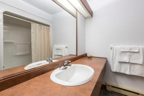 W łazience znajduje się biała umywalka i lustro. w obiekcie Hotel Baie Saint Paul w mieście Baie-Saint-Paul