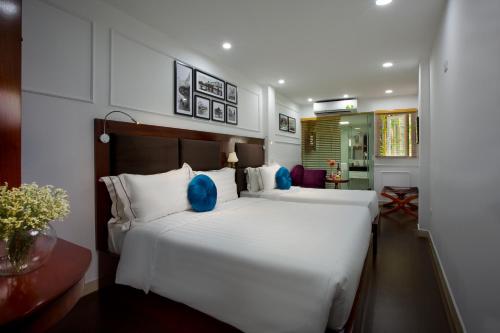 a bedroom with two beds with blue pillows at Antique Angel Hotel in Hanoi