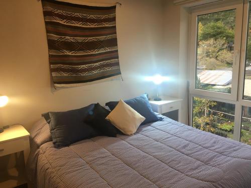 sypialnia z łóżkiem z poduszkami i oknem w obiekcie Umain 33 w mieście San Martín de los Andes