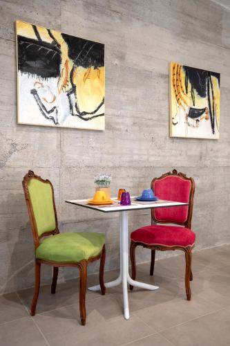 a table with two chairs and a table and two paintings at B&B Cantiere dell'anima - Rooms of art in Trapani