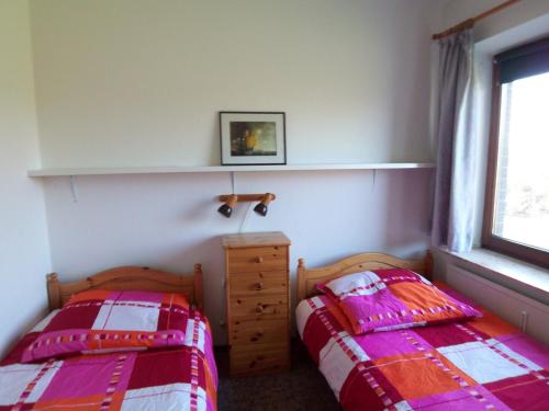 a bedroom with two beds and a dresser and a window at Deichblick in Friedrichskoog