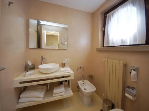W łazience znajduje się umywalka, toaleta i lustro. w obiekcie Hotel Dori w mieście Peschiera del Garda