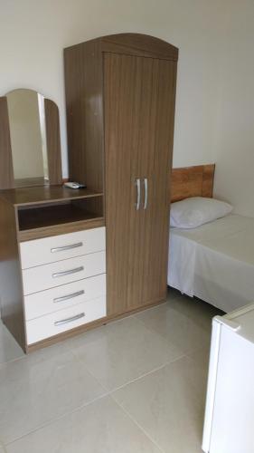 um armário de madeira num quarto com uma cama em Pousada Grota dos Coqueiros em Pirambu