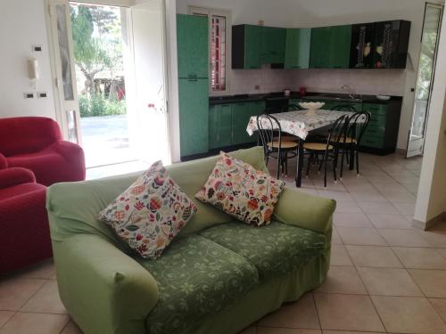 a living room with a green couch and a table at Profumo di Mare Fronte Spiaggia in Noto Marina