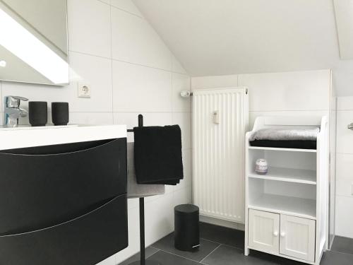 a white bathroom with a sink and a bed at Zollernalb-Apartment in Albstadt