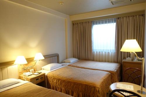 a hotel room with two beds and a window at Urayasu Beaufort Hotel in Urayasu