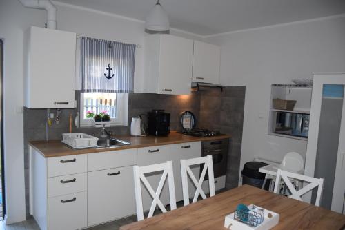 a kitchen with white cabinets and a wooden table at Dom w Pobierowie in Pobierowo