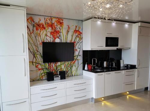 cocina con armarios blancos y TV en la pared en Cap d'Agde Naturist Apartments, en Cap d'Agde