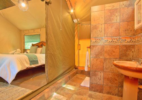 a bathroom with a bed and a shower and a sink at Kruger Adventure Lodge in Hazyview