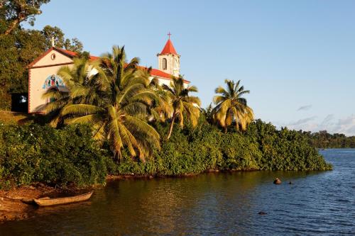 a church on a hill next to a river with palm trees at Hotel Vanivola & SPA in Sainte Marie