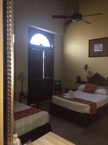 a hotel room with two beds and a window at Hotel San Miguel Arcangel in Izamal