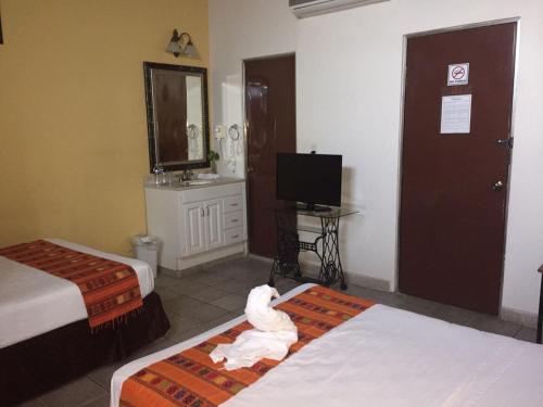a hotel room with two beds and a television at Hotel San Miguel Arcangel in Izamal