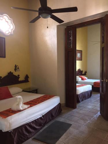 a bedroom with two beds and a ceiling fan at Hotel San Miguel Arcangel in Izamal