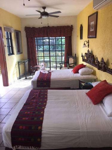 a bedroom with two beds and a window at Hotel San Miguel Arcangel in Izamal