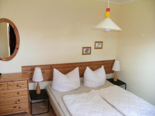 une chambre avec un lit avec des draps blancs et des oreillers dans l'établissement Gartenstraße 40d, à Karlshagen
