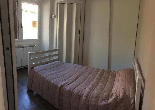 een slaapkamer met een bed in een kamer met een raam bij Maison Village Au Coeur De La Lavande in Valensole