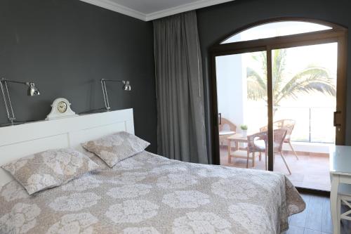 ein Schlafzimmer mit einem weißen Bett und einem Balkon in der Unterkunft Avenida de la Cornisa 11 in Puerto Rico de Gran Canaria