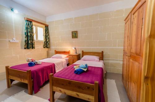 Zimmer mit 2 Betten und lila Bettwäsche in der Unterkunft Kaccatur Flats in Marsalforn