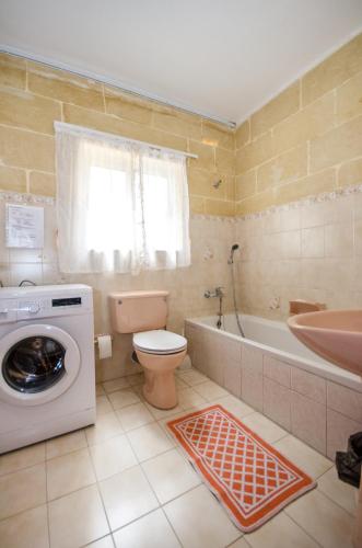 a bathroom with a toilet and a washing machine at Kaccatur Flats in Marsalforn