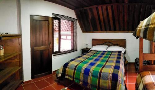a bedroom with a bed with a colorful comforter at Hotel Cabañas El Rincón de las Campanas in Nobsa