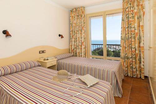 two beds in a room with a view of the ocean at Apartament Cap de Vol in Port de la Selva