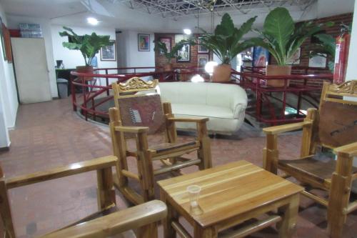 a living room with wooden chairs and a couch at Hotel Nuevo Tio in Valledupar