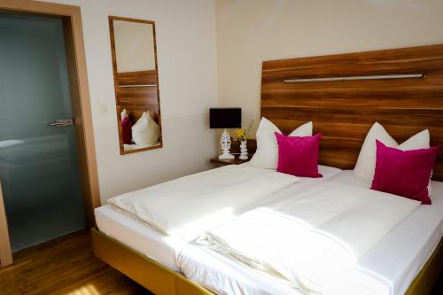 a bedroom with a large white bed with pink pillows at Hotel Burgwirt in Deggendorf