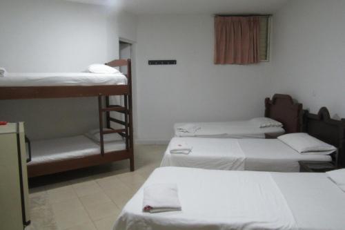 a room with three bunk beds and a chair at Hotel Nuevo Tio in Valledupar