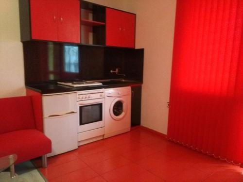 a kitchen with red cabinets and a washing machine at Studio Ekzarh in Varna City