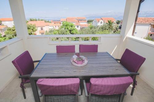 een houten tafel met paarse stoelen op een balkon bij Salsa in Supetar