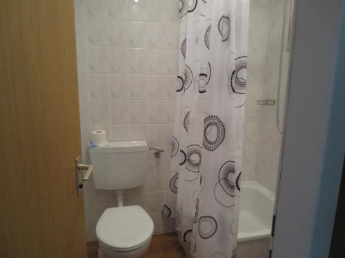 a bathroom with a toilet, sink, and shower curtain at Central-Hotel Tegel in Berlin