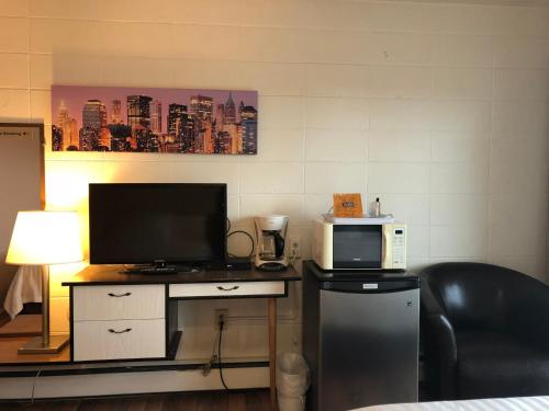 a room with a desk with a microwave and a television at Holiday House Motel in Ladysmith