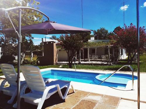 een paar stoelen en een parasol naast een zwembad bij Los Nogales de Yerua in Calabacillas