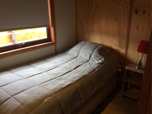 a bed in a small room with a window at Refugio Simple Sur Casa 4 personas in Malalcahuello