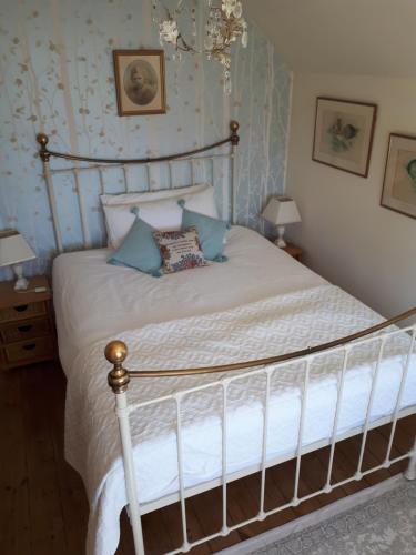 een slaapkamer met een bed met witte lakens en blauw behang bij Court Barn Cottage B&B in Burwash