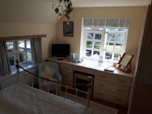 a bedroom with a desk with a computer and a bed at Court Barn Cottage B&B in Burwash