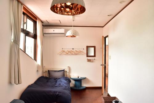 a bedroom with a bed and a table in it at Guest House Umusan in Nago