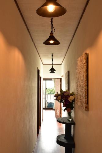 a hallway with two lights and a table with flowers at Guest House Umusan in Nago