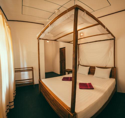 1 dormitorio con cama con dosel y sábanas blancas en Peak House, en Hiriketiya