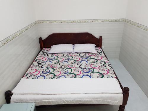 a small bed with a quilt and two pillows at Minh Kim Guesthouse in Ấp Phó