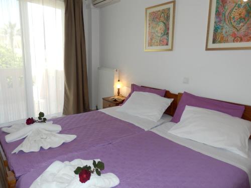 een slaapkamer met een paars bed met handdoeken erop bij Charisma Apartment in Plataniás
