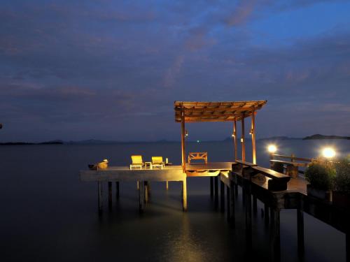 a dock with chairs on the water at night at Fresh House in Ko Lanta