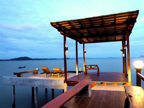 een houten terras met stoelen en een paviljoen op het water bij Fresh House in Koh Lanta