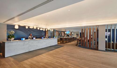 a lobby with a bar with people sitting at it at Hyatt Place London Heathrow Airport in Hillingdon