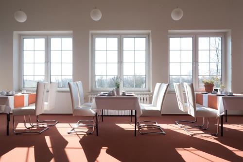 a dining room with white chairs and tables and windows at Haus ÜberLand in Sundhagen