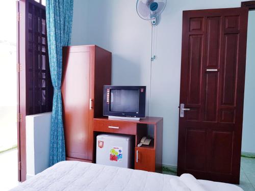 Schlafzimmer mit einem Bett, einem TV und einer Tür in der Unterkunft Minh Hien Hotel in Vũng Tàu